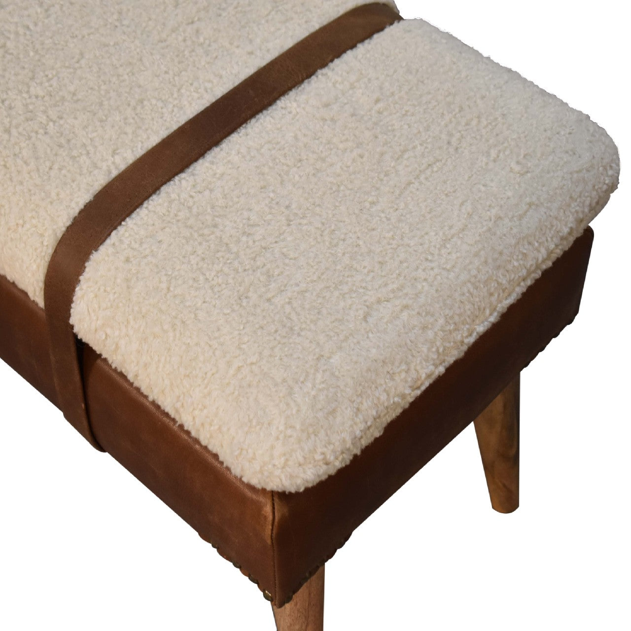 This is an overhead-angled view of the Boucle Buffalo Hide Leather Bench, highlighting the rich texture of the handwoven bouclé cushion. The buffalo leather, solid wood legs, and belted strap detail are also visible.