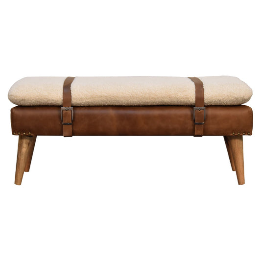 A front view of a rustic-style tan buffalo hide leather bench with an off-white, handwoven bouclé cushion, oak-finished solid wood legs, and belted strap accents.