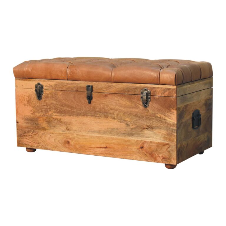 This left end angle of a leather storage trunk highlights the sturdy, solid mango wood with an oak finish and the pillowed medium-dark tan buffalo hide upholstery.